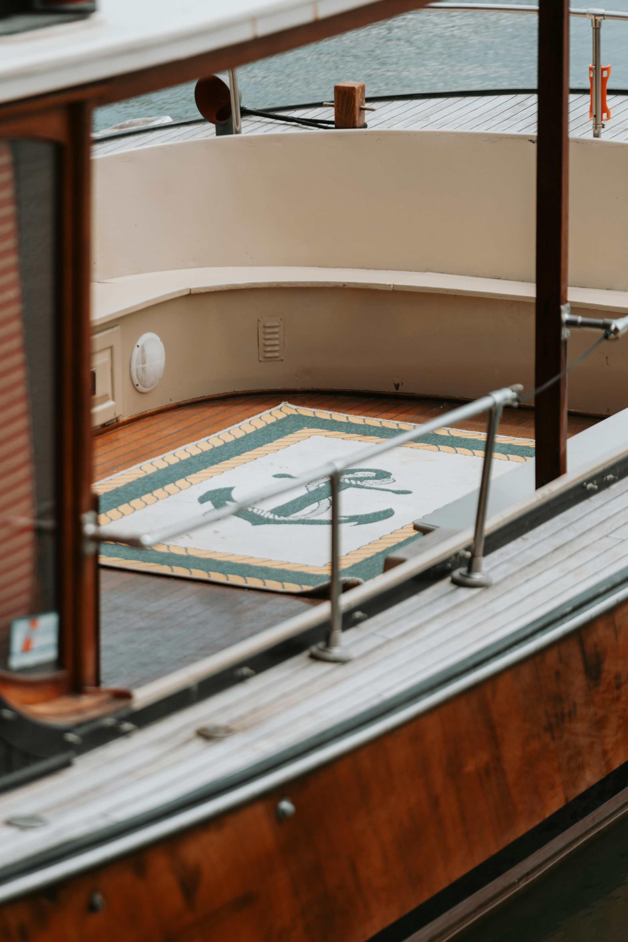 A yacht’s wooden deck and seating area seen through the cabin glazing